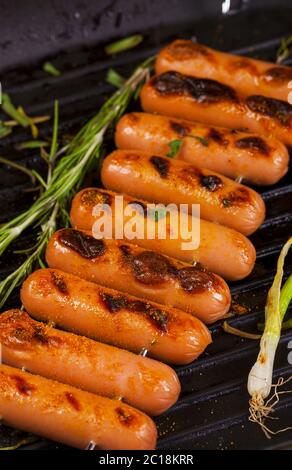 Fried sausages with herbs, spices and vegetables in a pan close up. Stock Photo