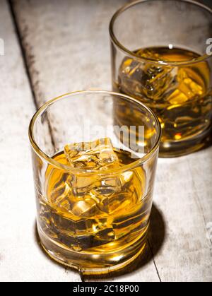 Two glasses of whiskey with ice cubes served on white wooden planks. Stock Photo