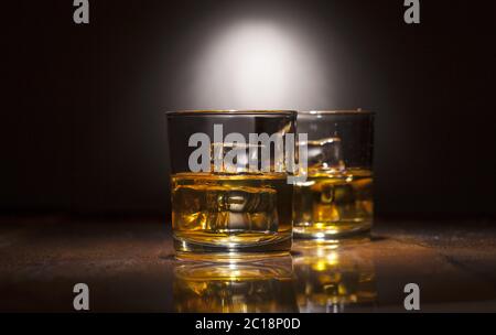 Two glasses of whiskey with ice cubes served on wooden planks. Stock Photo