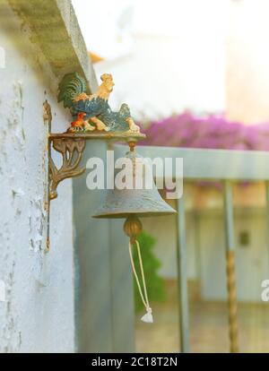 The Small iron bell with colored rooster outside the house. Stock Photo