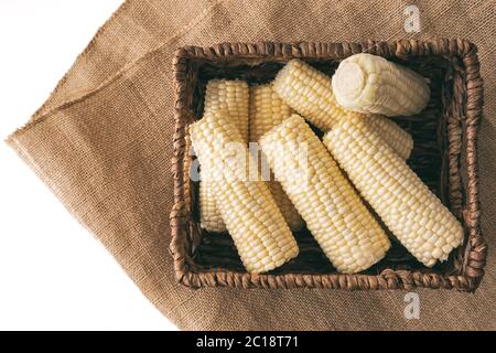 Corn in a basket. Raw organic corn in wicker basket close up isolated on white background Stock Photo
