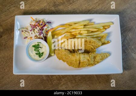 British Traditional fish and chips and tartar sauce and served with coleslaw. Stock Photo