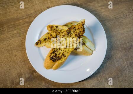 3 sliced of grilled garlic breads served on white plate. Stock Photo