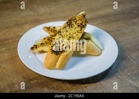 3 sliced of grilled garlic breads served on white plate. Stock Photo