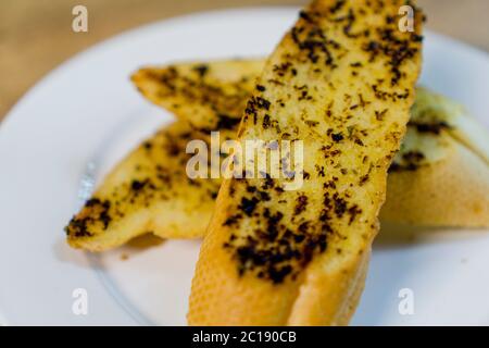 3 sliced of grilled garlic breads served on white plate. Stock Photo