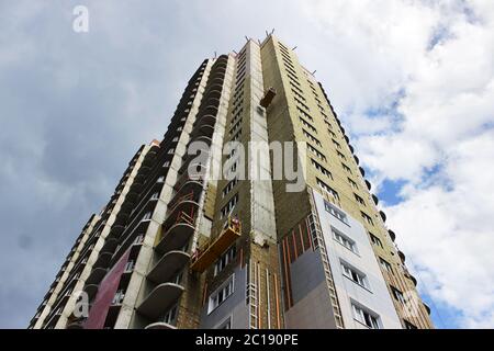 worker in yellow front suspended cradle on a newly built high-rise building Stock Photo