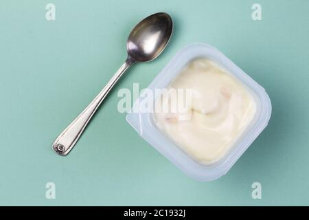 Healthy yellow fruit flavored yoghurt with natural coloring in plastic cup isolated on green backgro Stock Photo