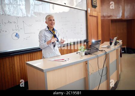 Female elderly professor giving a lecture from cathedra Stock Photo