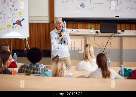 Elderly professor bored with students on lecture in amphitheater Stock Photo