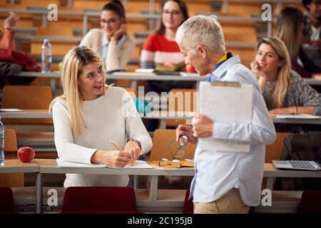 Elderly professor answering student's questions in amphitheater Stock Photo