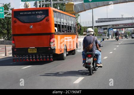 SAMUT PRAKAN, THAILAND, JUN 03 2020, A motorcycle goes around a city bus on the street. Stock Photo