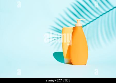 Orange containers for lotion without label on blue background with leaf, space for text Stock Photo