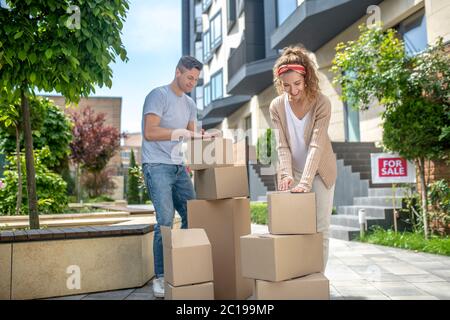 Young couple packing cardboards before moving to a new house and looking involved Stock Photo