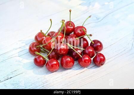 Pile of fresh red cherries on a market table outdoors in the sunshine placed in the centre of the frame with copy space Stock Photo