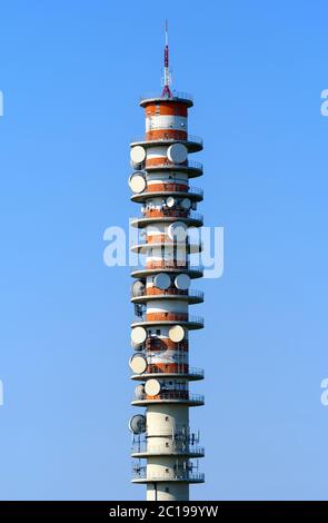 Elevated telecommunications repeater tower with dishes allowing communication by line of site between two stations against a blue sky Stock Photo