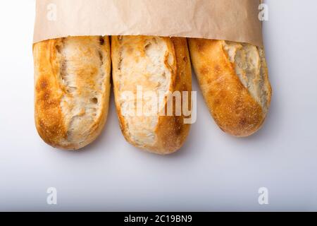 French bread rolls in the paper bag isolated on light background. Stock Photo