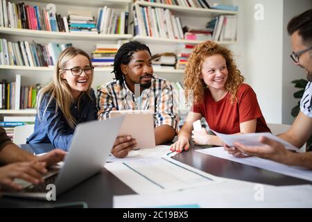 Young architect colleagues are analyzing blueprints while working on a new project Stock Photo