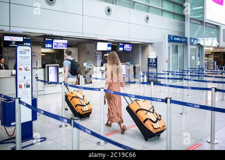 Duesseldorf, Germany. 15th June, 2020. Two travellers to Mallorca go with suitcases to a check-in counter at Düsseldorf Airport. After the travel warning for 27 European countries was lifted in the night to Monday (15.06.2020), this morning for the first time a plane with holidaymakers took off from Düsseldorf Airport after a corona break of weeks. According to an airport spokesman, Tui-Flight X3 2312 to the Mediterranean island of Mallorca took off at 8.55 a.m. - with a 45-minute delay. Credit: Marcel Kusch/dpa/Alamy Live News Stock Photo