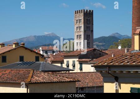 View over the rooftops of Lucca, walled city in Tuscany, Italy, including the San Frediano bell tower, with the Apuan Alps in the distance Stock Photo