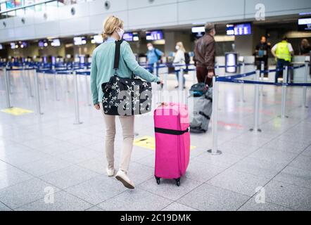Duesseldorf, Germany. 15th June, 2020. Travellers to Mallorca go to a check-in counter at Düsseldorf Airport. After the travel warning for 27 European countries was lifted in the night to Monday (15.06.2020), this morning for the first time ever a plane with holidaymakers took off from Düsseldorf Airport after a corona break of weeks. According to an airport spokesman, Tui-Flight X3 2312 to the Mediterranean island of Mallorca took off at 8.55 a.m. - with a 45-minute delay. Credit: Marcel Kusch/dpa/Alamy Live News Stock Photo
