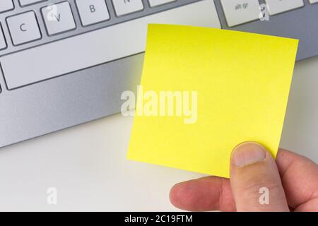 Human hand holding yellow sticky note Stock Photo