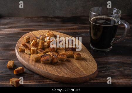 Homemade tradishional russian kvass in cup and rusk on cutting board on wooden background. Wonderful healthy refreshing drink for summer Stock Photo