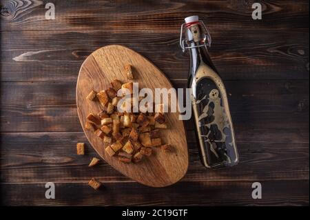 Top view homemade tradishional russian kvass in bottle and rusk on cutting board on wooden background. Wonderful healthy refreshing drink for summer Stock Photo