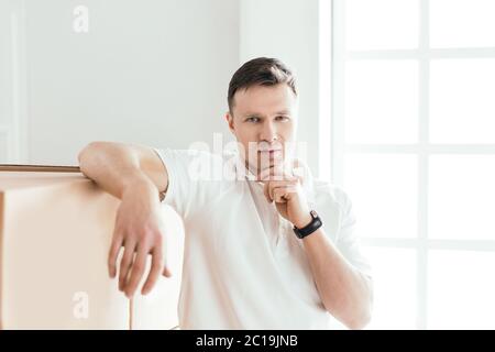 pensive young man standing near cardboard boxes Stock Photo