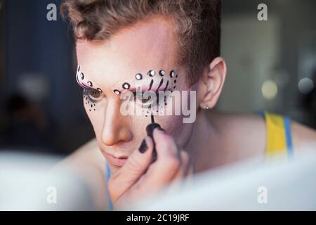 A young man applying drag makeup. Bad, Smokey eye Makeup Stock Photo