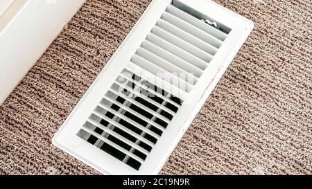 Panorama White air conditioner duct grille cover against floor with brown carpet Stock Photo