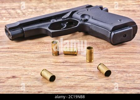 Pistol with empty cartridges on a wooden table Stock Photo