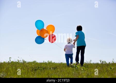 Little boy, toddler, child playing with colorful balloons in the park on kids day, sunny summer afternoon in nature Stock Photo