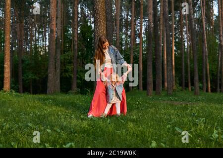 woman with little toddler daughter walk and dance on the lawn in the park Stock Photo