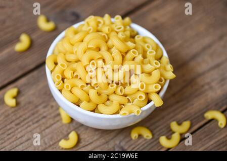raw macaroni uncooked delicious pasta or penne noodles / macaroni on bowl and wooden background , top view Stock Photo