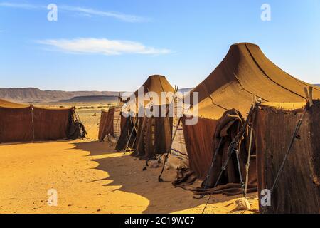 Tents in the middle of desert with mountains in the background, on a sunny day Stock Photo