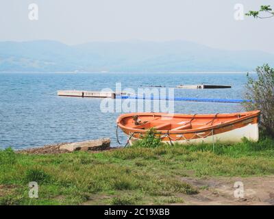 An orange fishing boat is located on the seashore. Russia, the village of Slavyanka Stock Photo