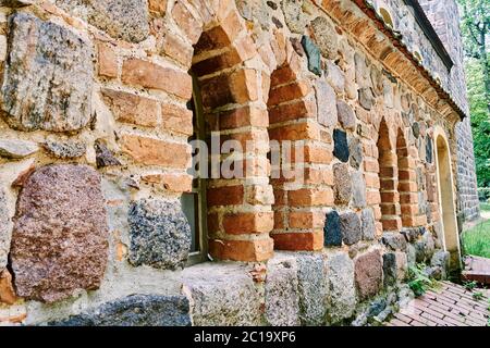 Details of a historic medieval church in Berlin, Germany. You can see a series of windows in a field stone wall. Stock Photo