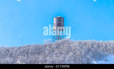 Panorama Snow covered Wasarch Mountains in winter with water tank tower against blue sky Stock Photo