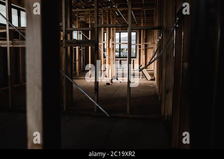 A construction set of a house being built with exposed wires and wooden beams, light shining in on the tools Stock Photo