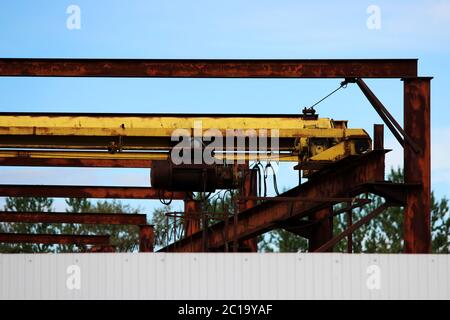 old rusty crane beam in the warehouse under the open sky near the building supermarket for handling operations. Stock Photo