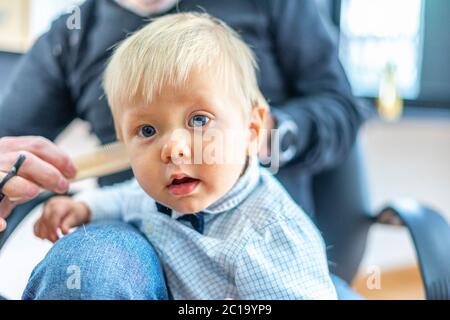 Blond baby boy with blue eyes at the hairdresser salon Stock Photo