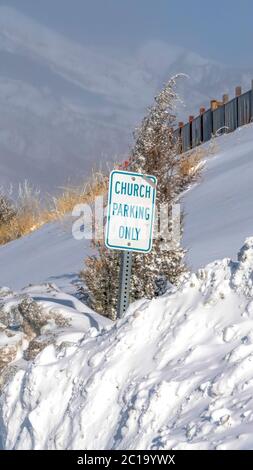 Vertical crop Building and Church Parking Only sign on the snowed in slope of Wasatch Mountain Stock Photo