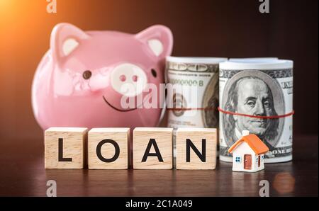 Real estate sale, savings, home loans market concept. model house with text loan on wooden cube, smilely pink Piggy bank and bank note Stock Photo
