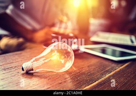 Light blub on the table and blur business working back. Stock Photo
