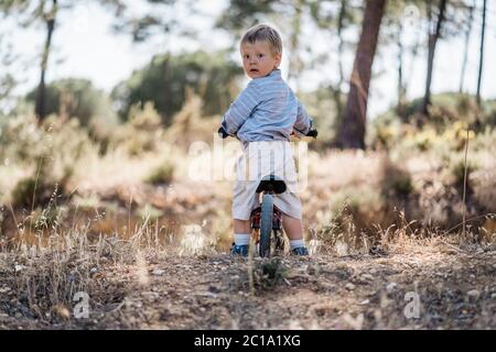 Cute toddler on bicycle looking back as waiting for the rest Stock Photo
