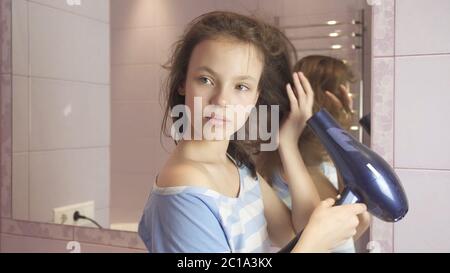 Beautiful teen girl dries hair a hairdryer in bathroom Stock Photo