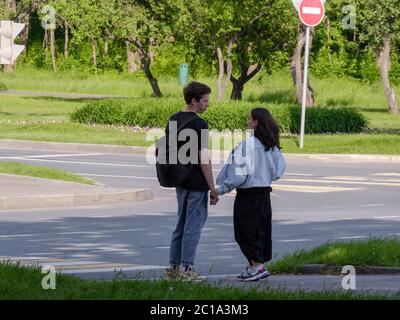 Moscow, Russia. June 14, 2020. A pair of lovers at a crossroads in front of a pedestrian crossing on a sunny summer day. Lovers hold hands and look at Stock Photo