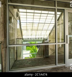 Square Glass door and wall with view of slanted frosted roof over stairway of building Stock Photo