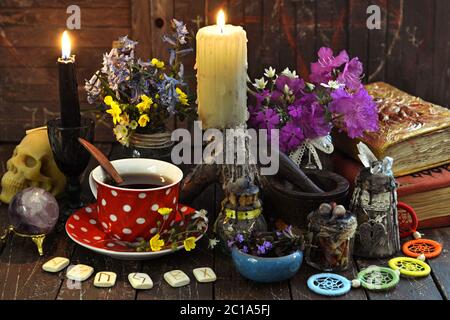 Witch books, cup of tea, runes and burning candles on the table. Esoteric, wicca and occult background with magic objects, fortune telling and divinat Stock Photo