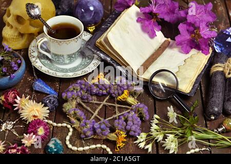 Pentagram with dry flowers, open diary and cup of coffee on witch table. Esoteric, wicca and occult background with magic objects, fortune telling and Stock Photo